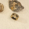 Gold ring with embedded stones on a textured beige surface