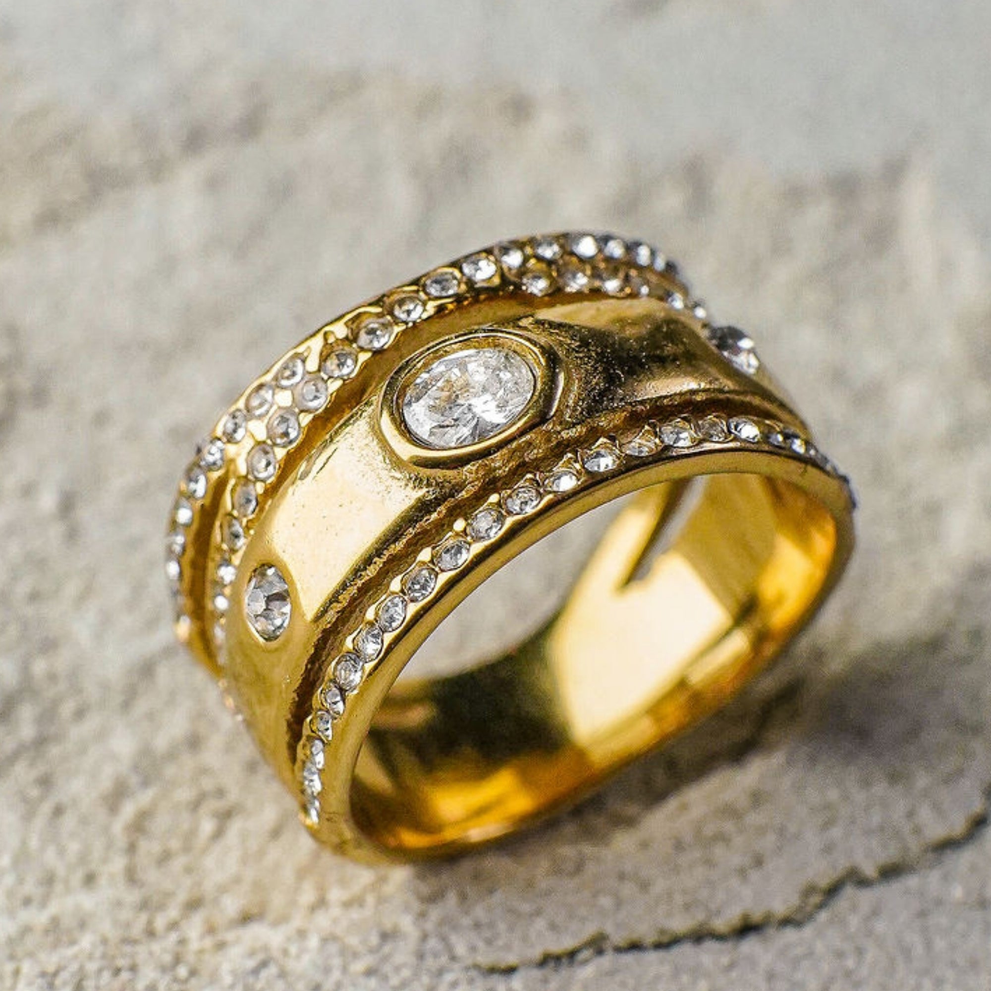 Gold ring with diamond accents on a textured surface