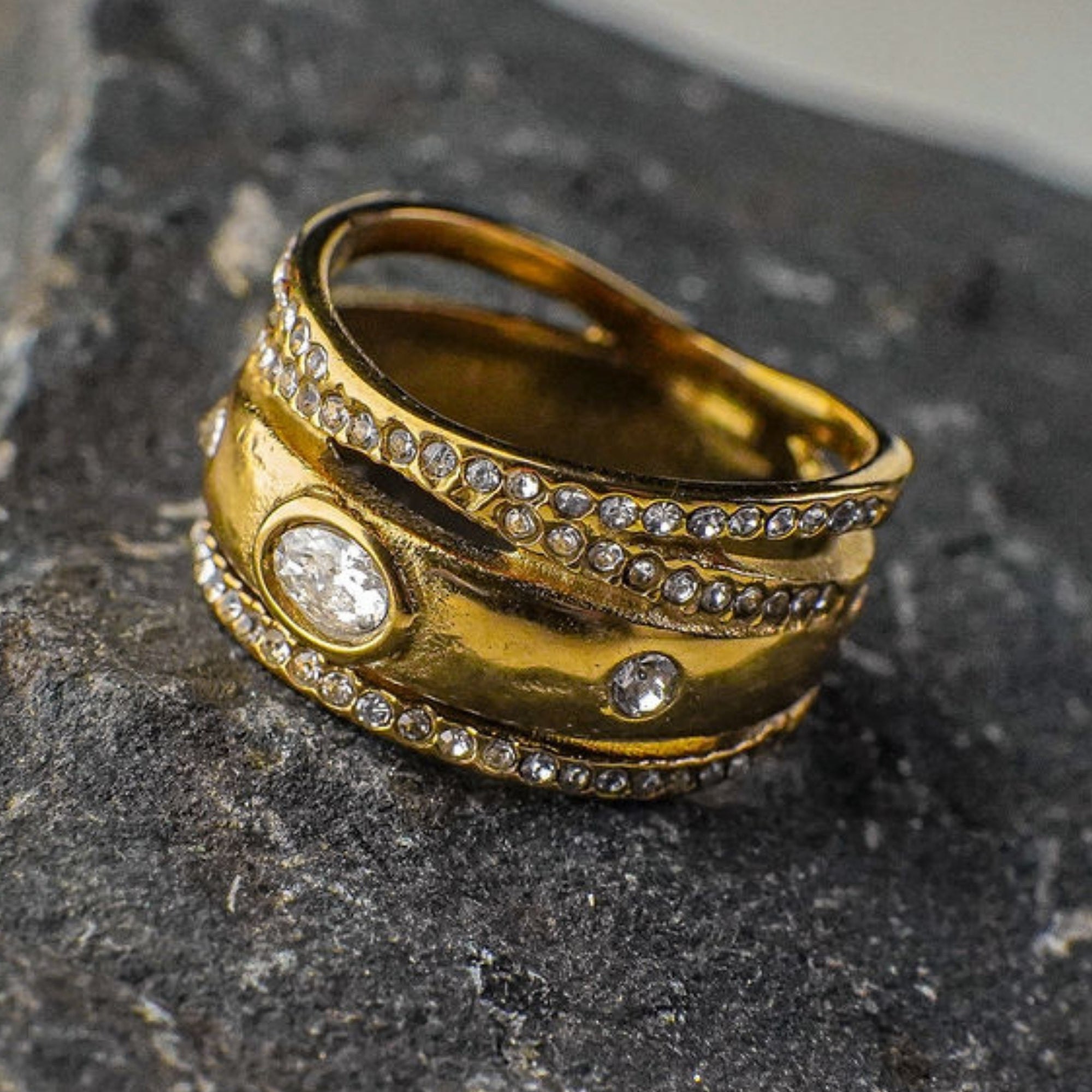 Gold ring with embedded stones on a dark stone surface