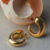 Gold hoop earrings on a textured surface with an open shell in the background