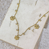 Gold necklace with floral pendants on a textured surface