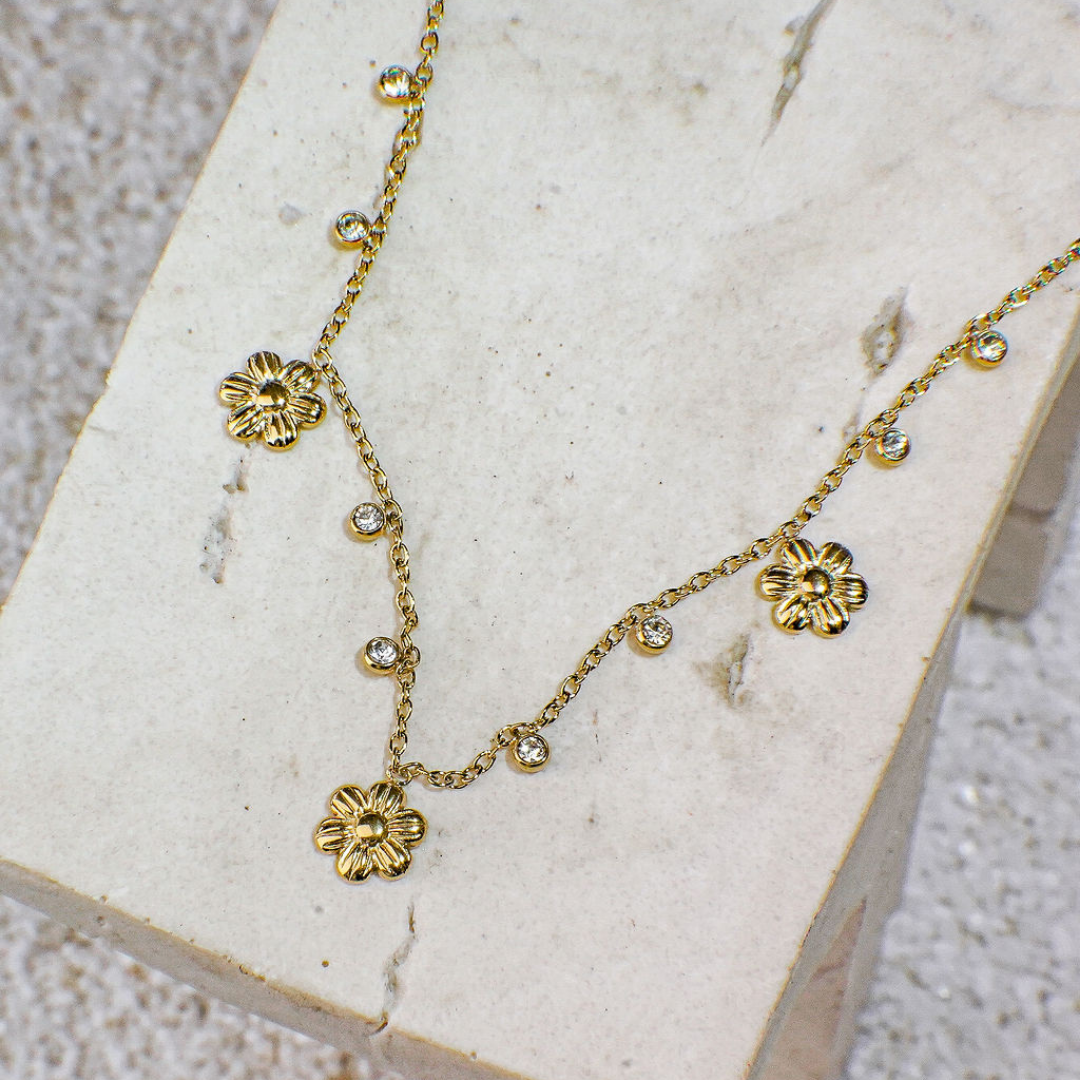 Gold necklace with floral pendants on a textured surface