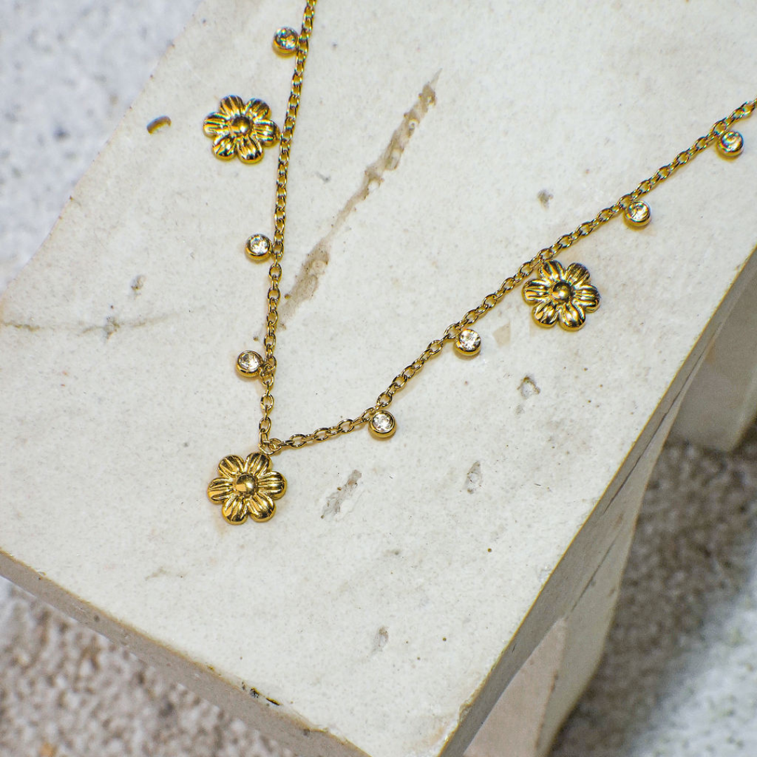 Gold floral necklace on a textured white surface