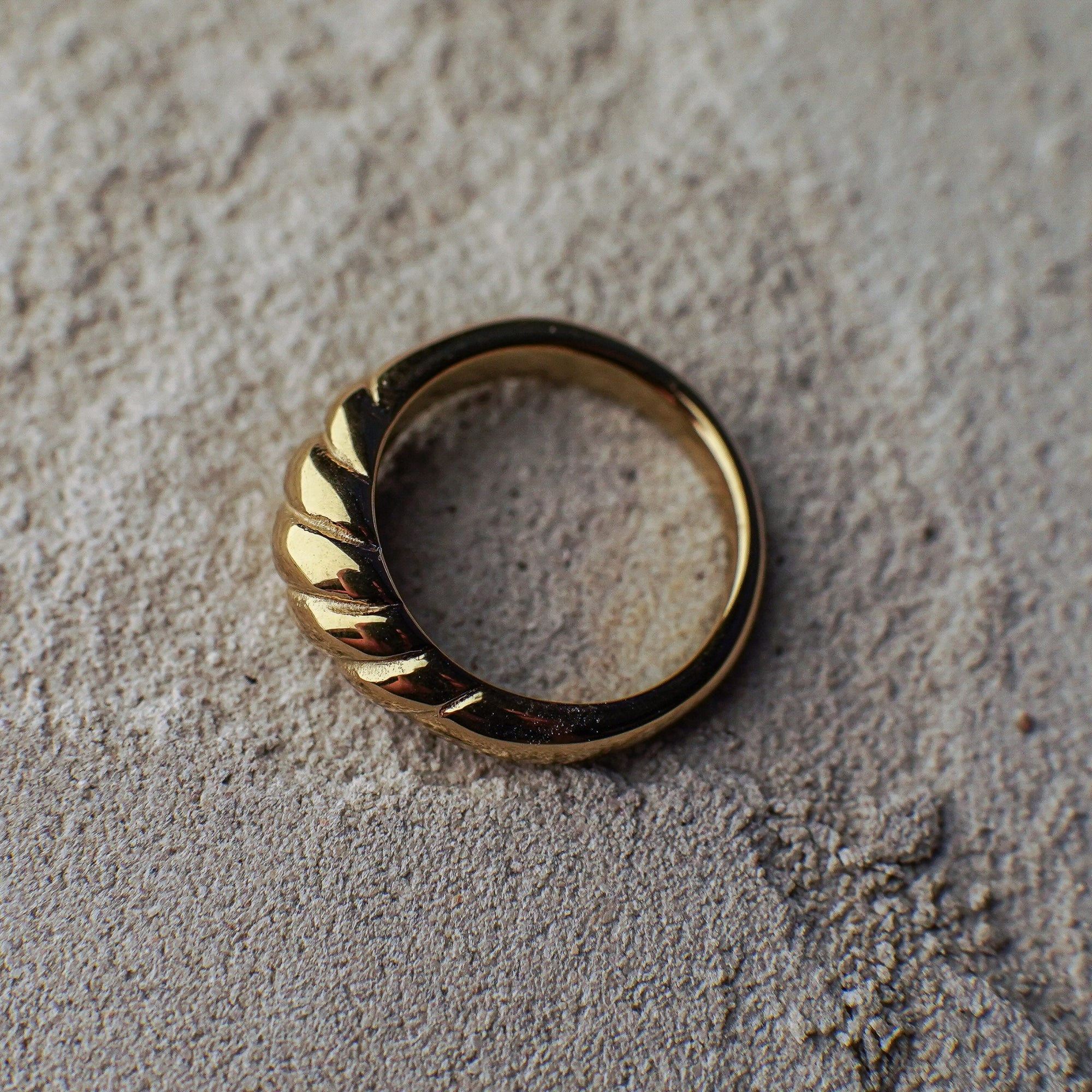 Gold ring with a textured band on a textured surface