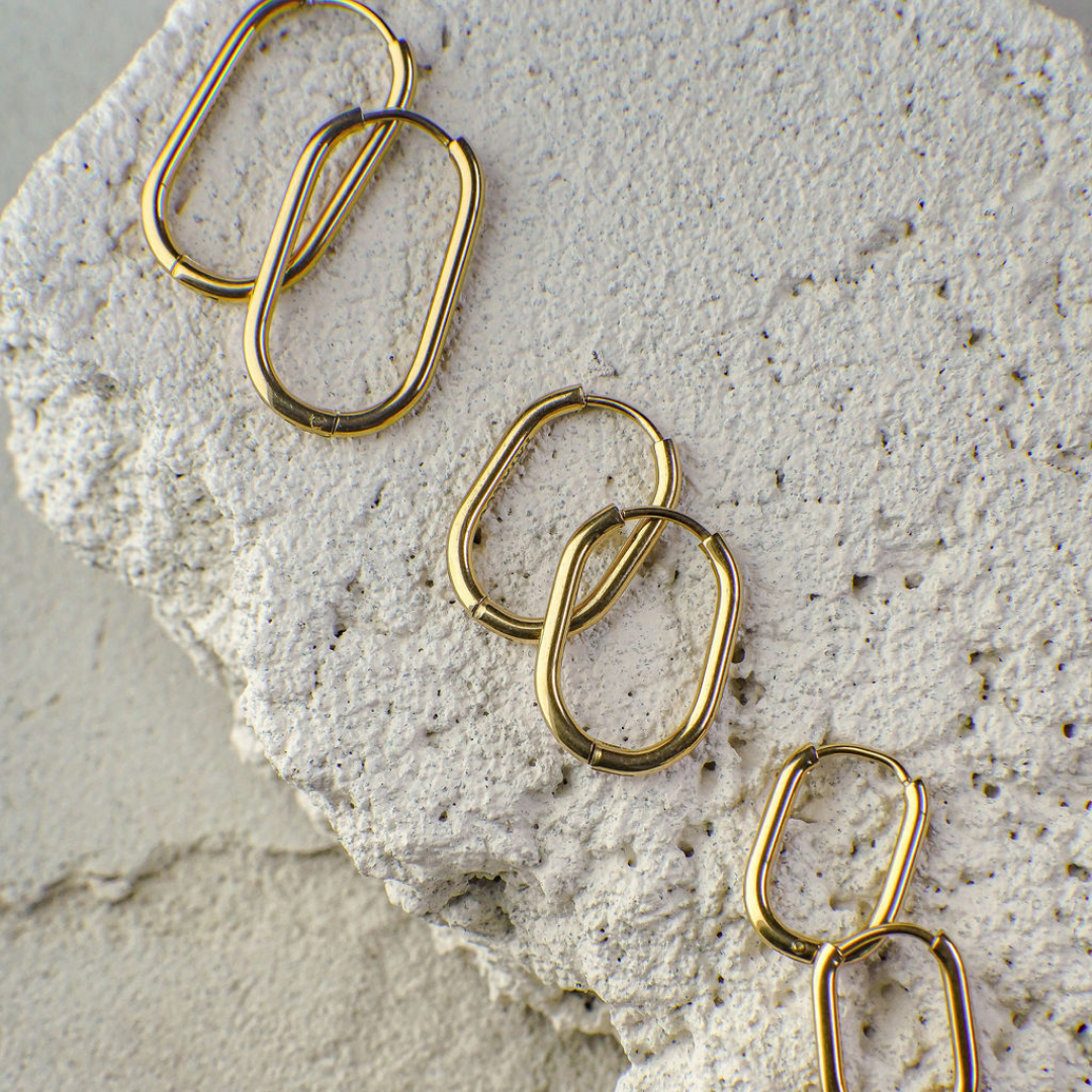 Gold hoop earrings on a textured stone surface