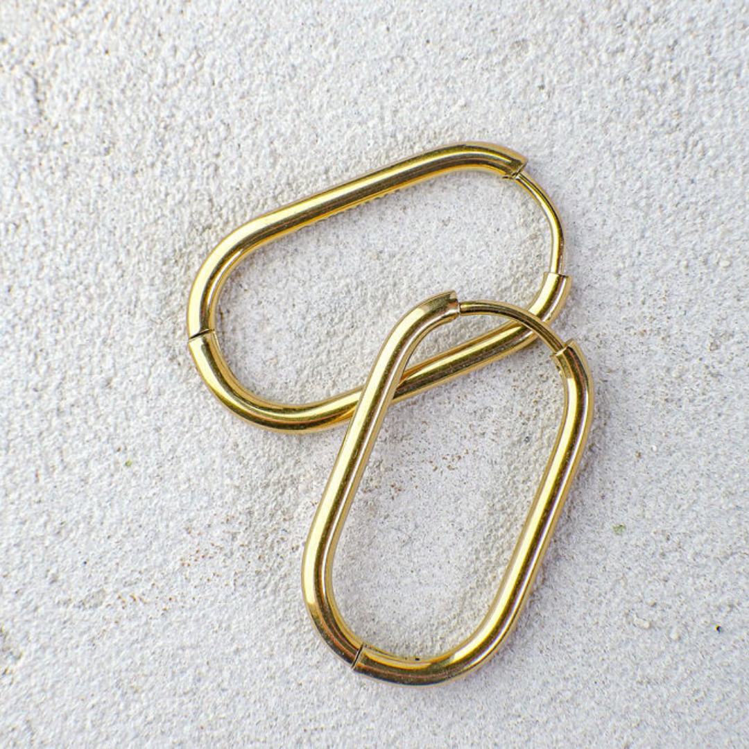 Pair of gold hoop earrings on a textured white surface