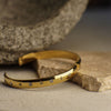 Gold bracelet with small stones on a stone surface