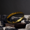 Gold bracelet with embedded stones on a dark stone surface