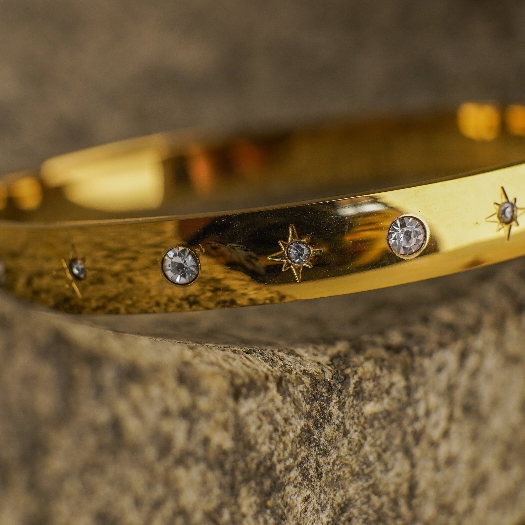 Gold bracelet with gemstone accents on a textured surface