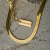 Gold chain bracelet with 'FAYA&CO' tag on a textured surface