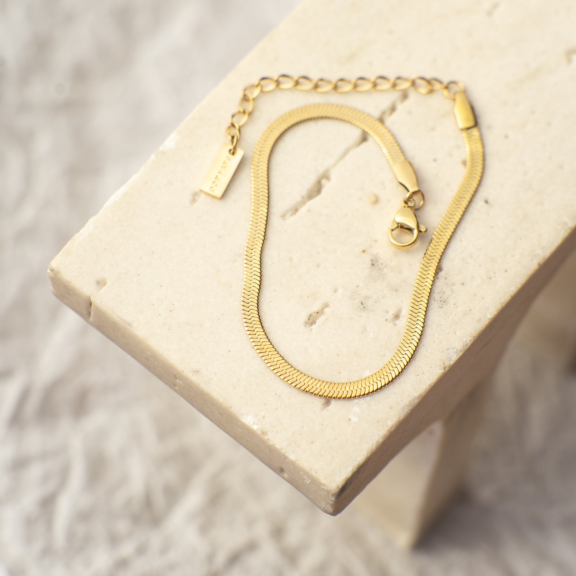 Gold necklace on a beige stone surface
