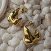 Gold earrings on a textured white stone surface