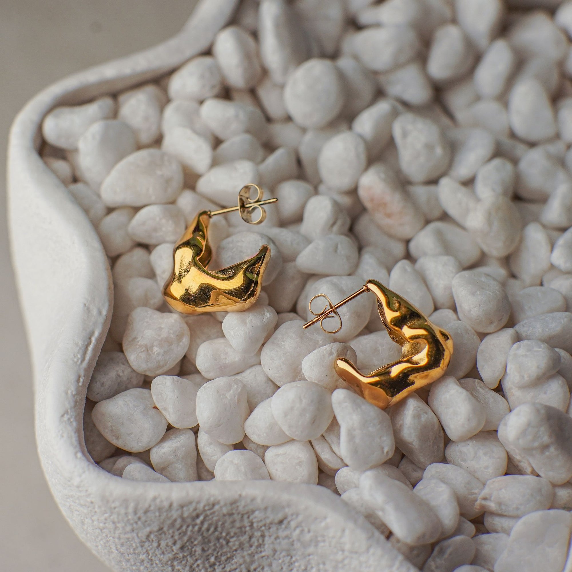 Gold hoop earrings on a bed of small white stones