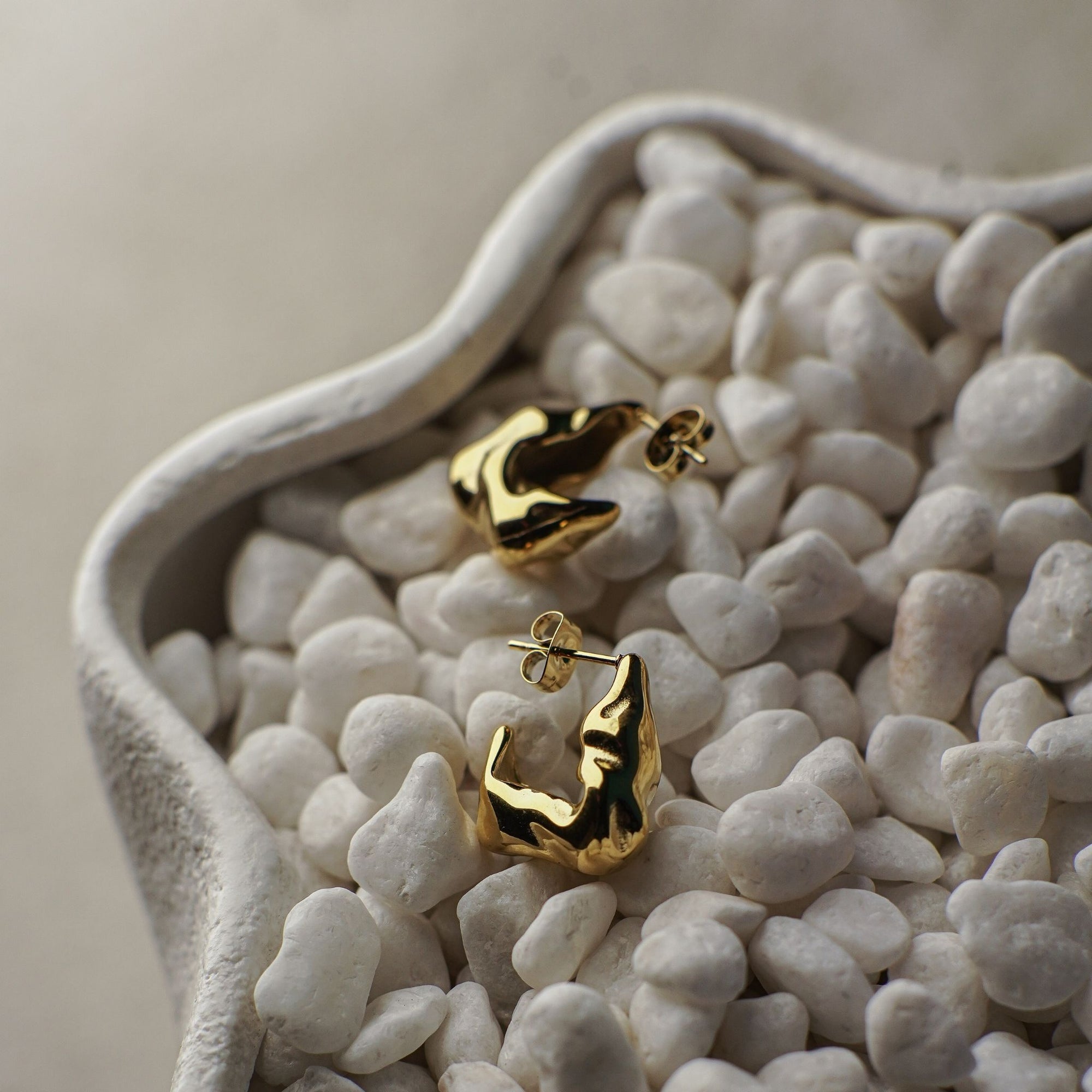Gold earrings on a bed of small white stones