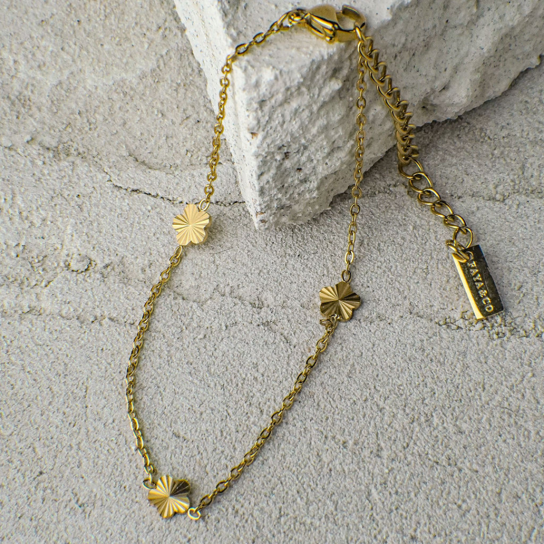 Gold bracelet with floral designs on a textured stone surface
