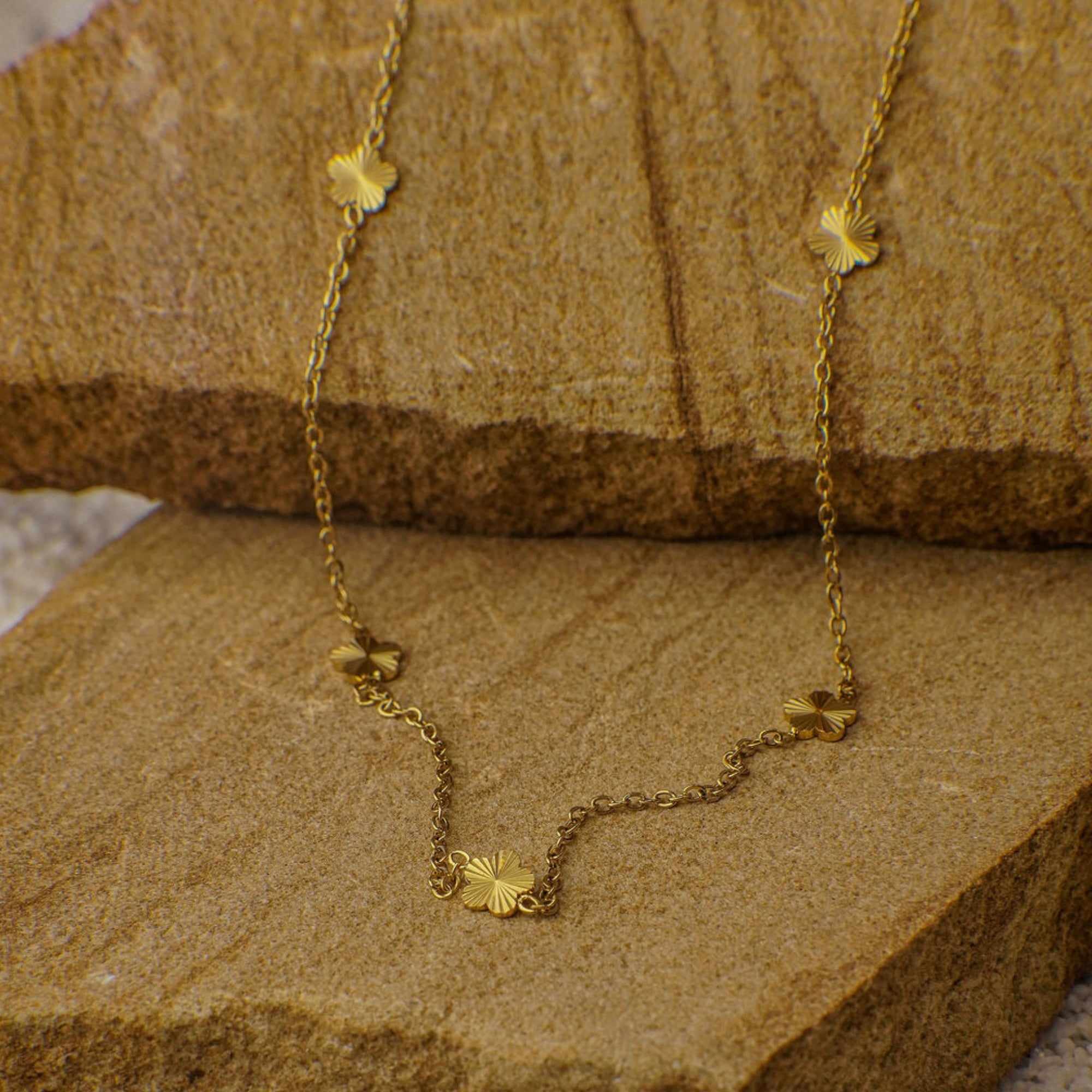 Gold necklace with floral pendants on a wooden surface