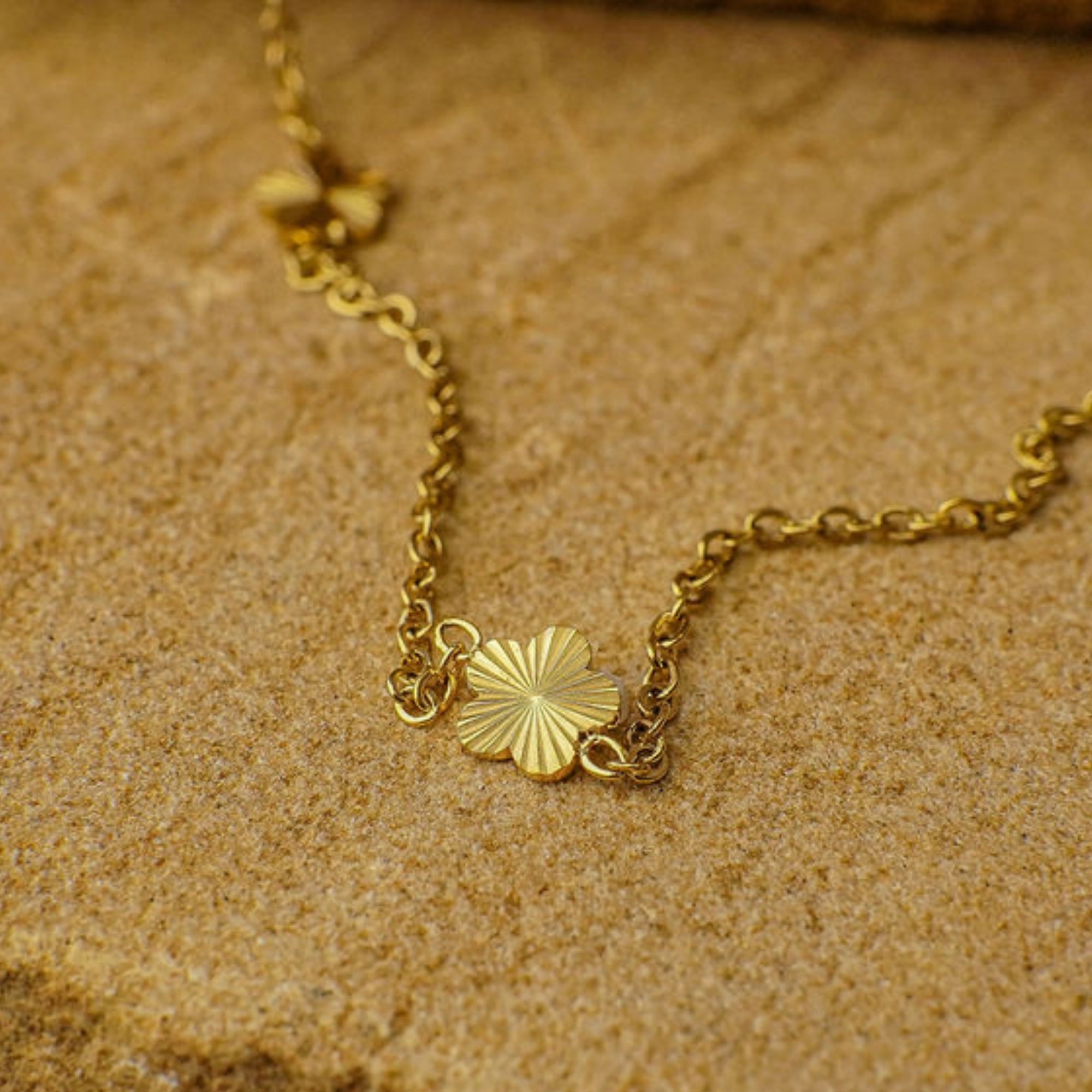 Gold necklace with a sunflower pendant on a textured brown surface