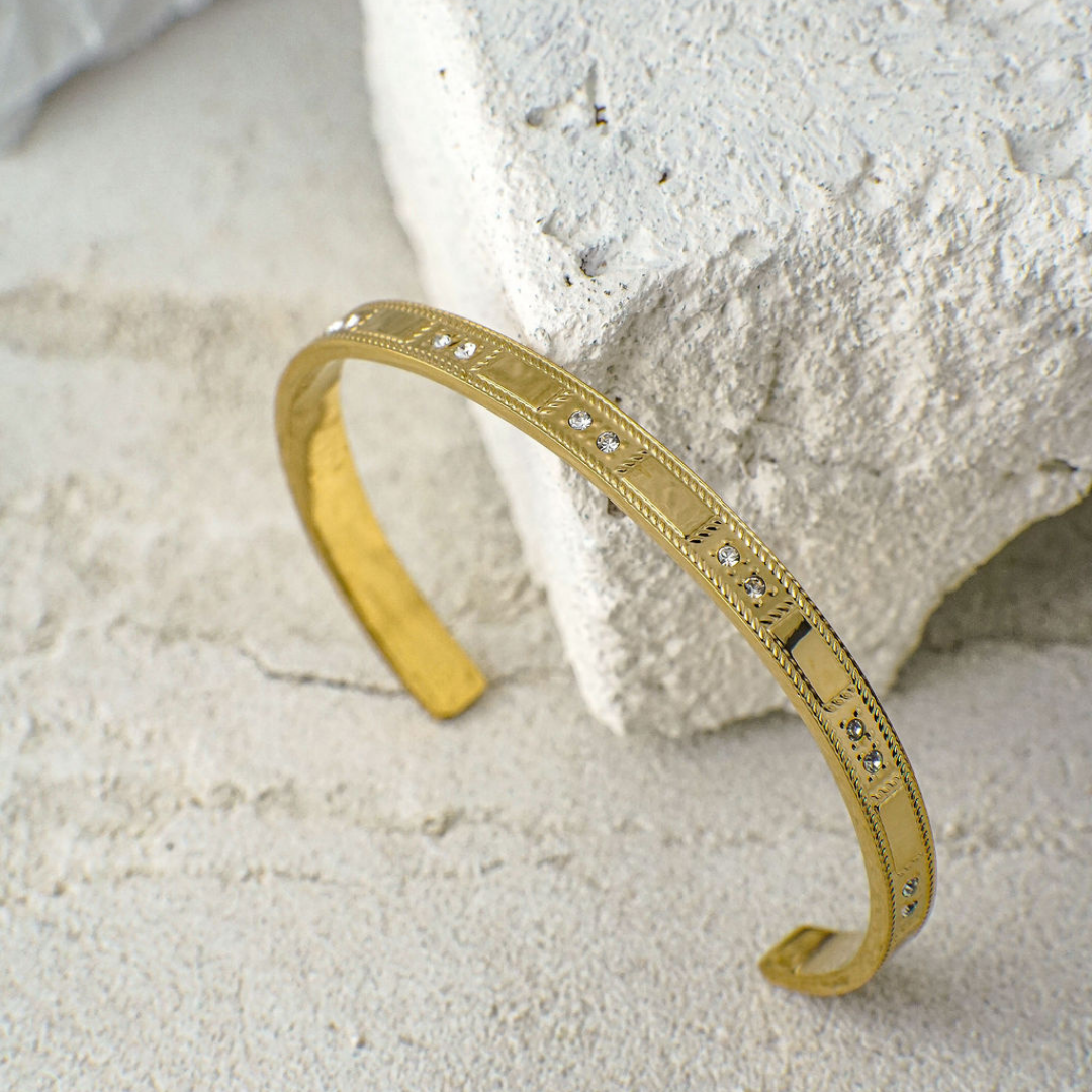 Gold bracelet with diamond accents on a textured stone surface