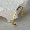 Gold bracelet with embedded stones on a textured stone surface