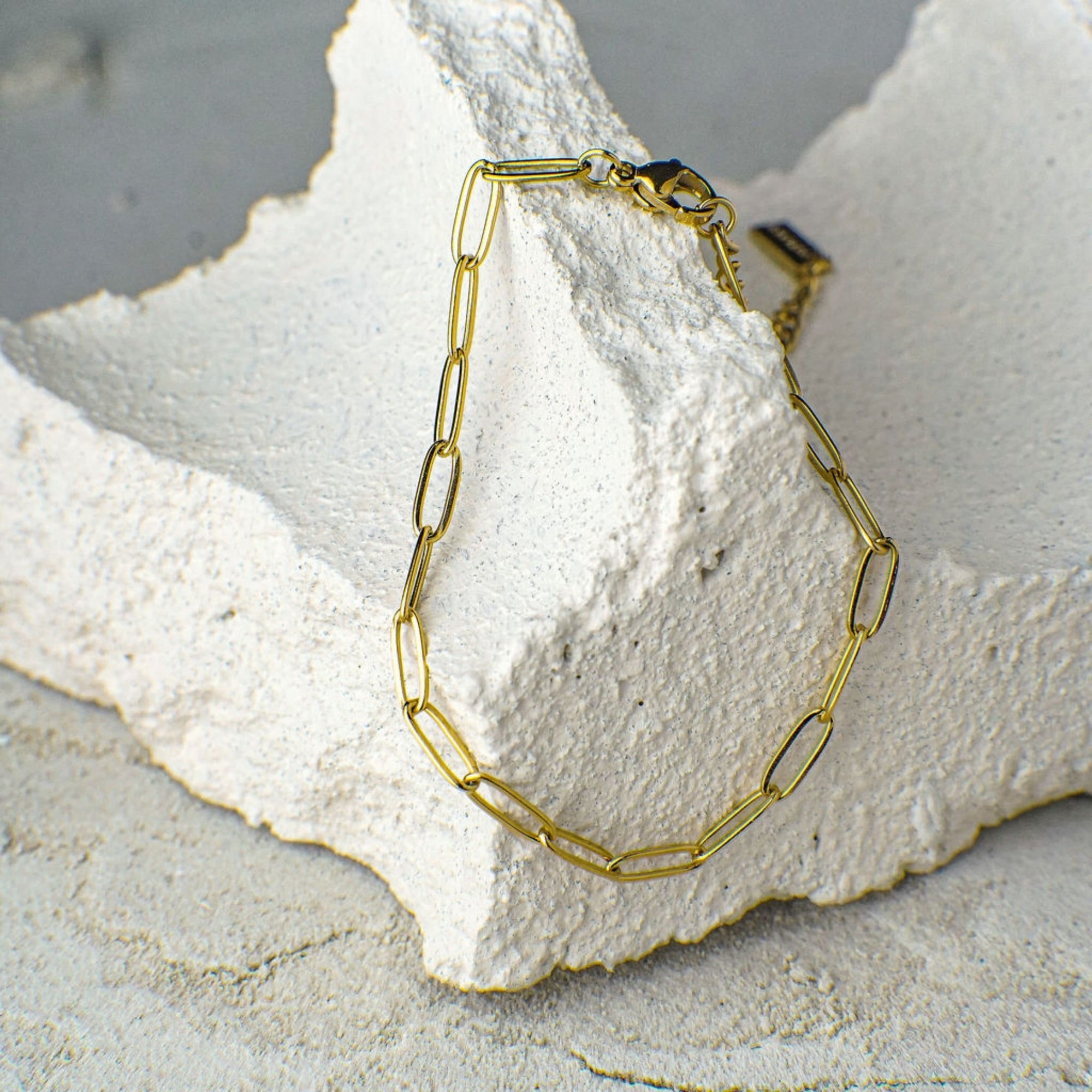 Gold chain bracelet on a textured white surface