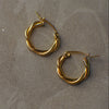 Gold hoop earrings on a gray surface
