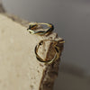 Gold hoop earrings on a textured stone surface with a neutral background