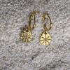 Gold hoop earrings with textured designs on a textured surface