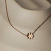 Rose gold necklace with a circular pendant on a neutral background