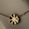 Rose gold necklace with a sun-shaped pendant on a neutral background