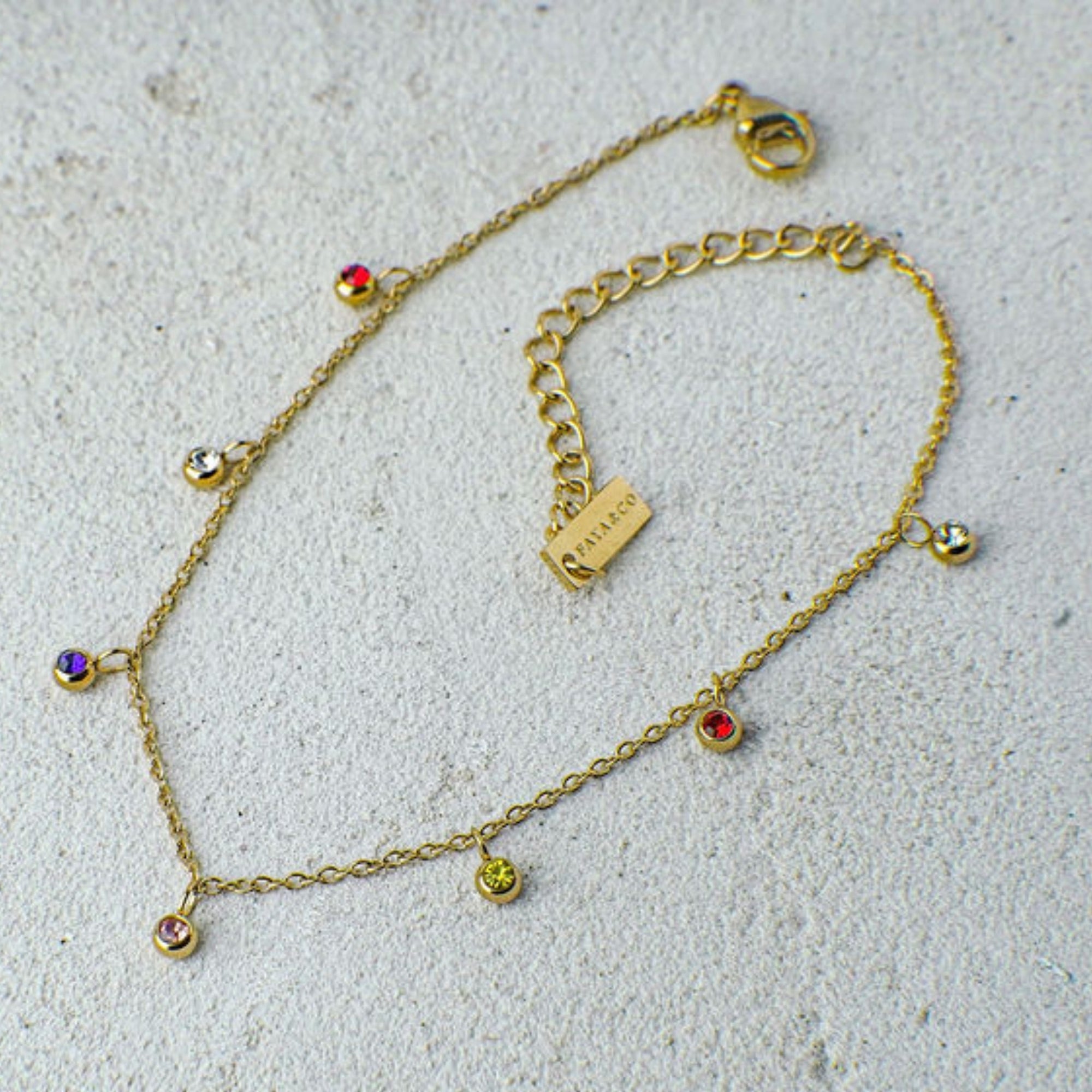 Gold necklace with colorful beads on a light gray surface