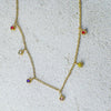 Gold necklace with colorful gemstones on a textured surface