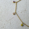 Gold necklace with gemstone pendants on a textured surface