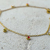 Gold necklace with small gemstones on a textured surface