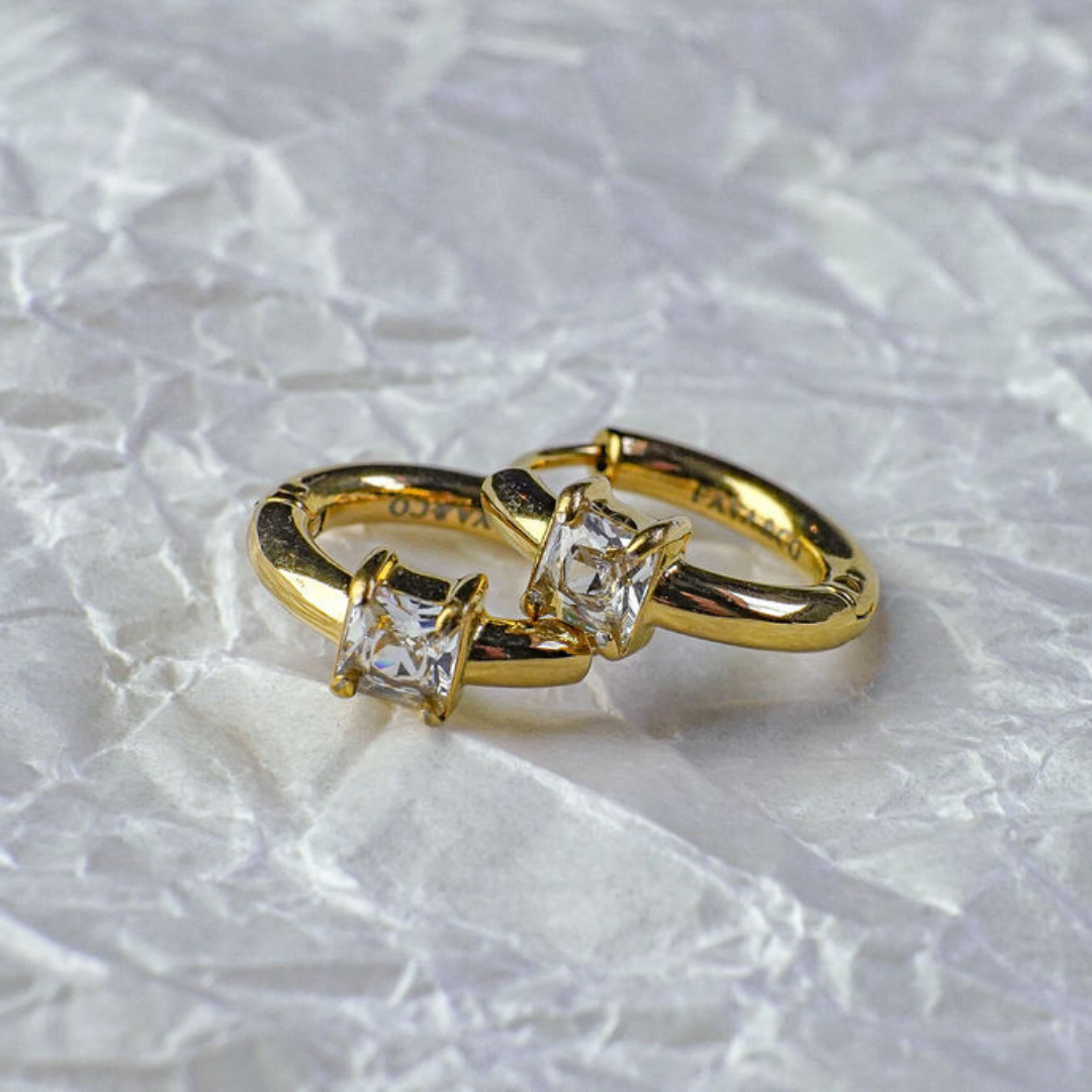 Gold ring with two square-cut diamonds on a textured white background