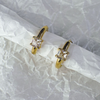 Gold hoop earrings with clear gemstones on a textured white background