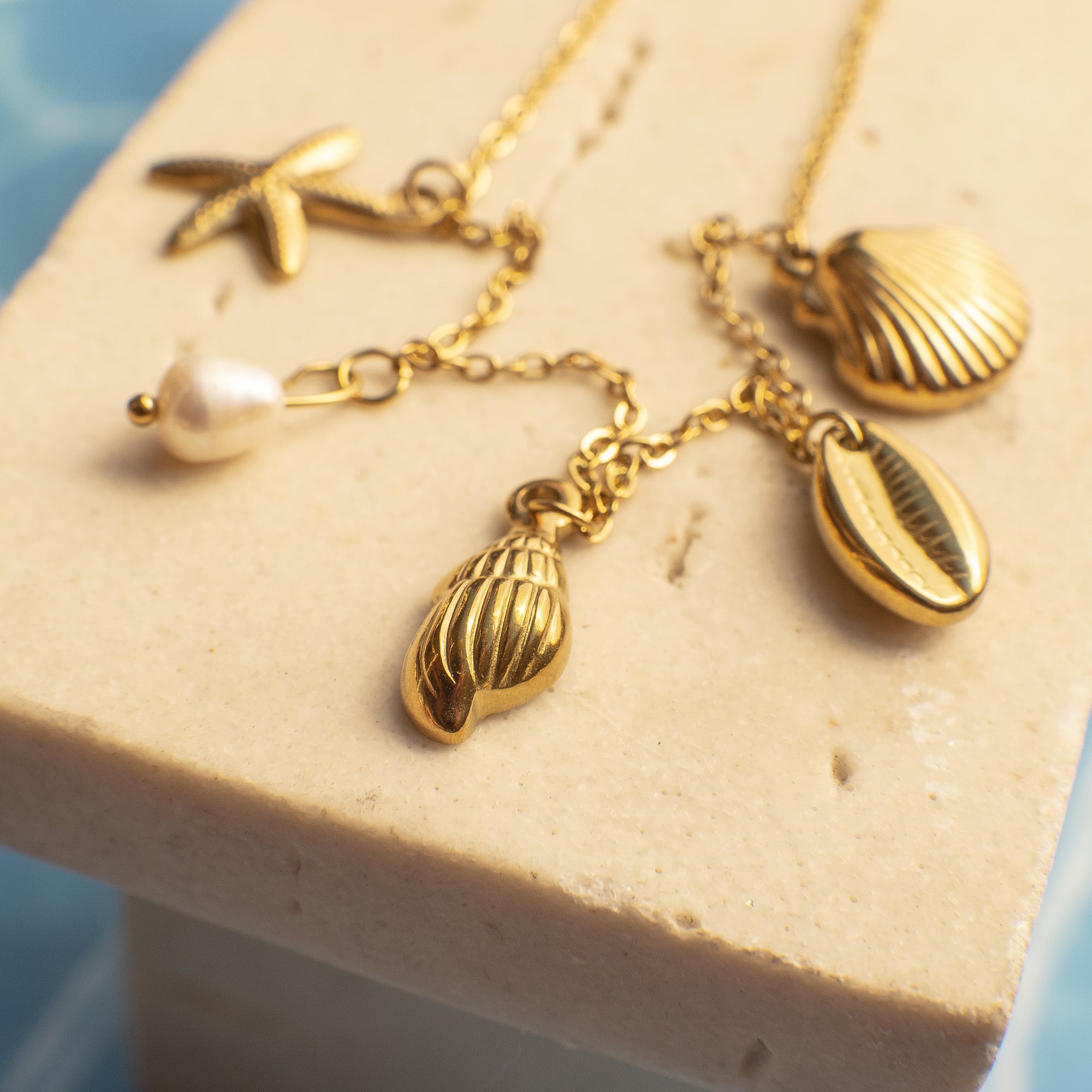 Gold necklace with various charms on a textured surface