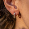 A model wearing a rose gold hoop earring with little crystals.