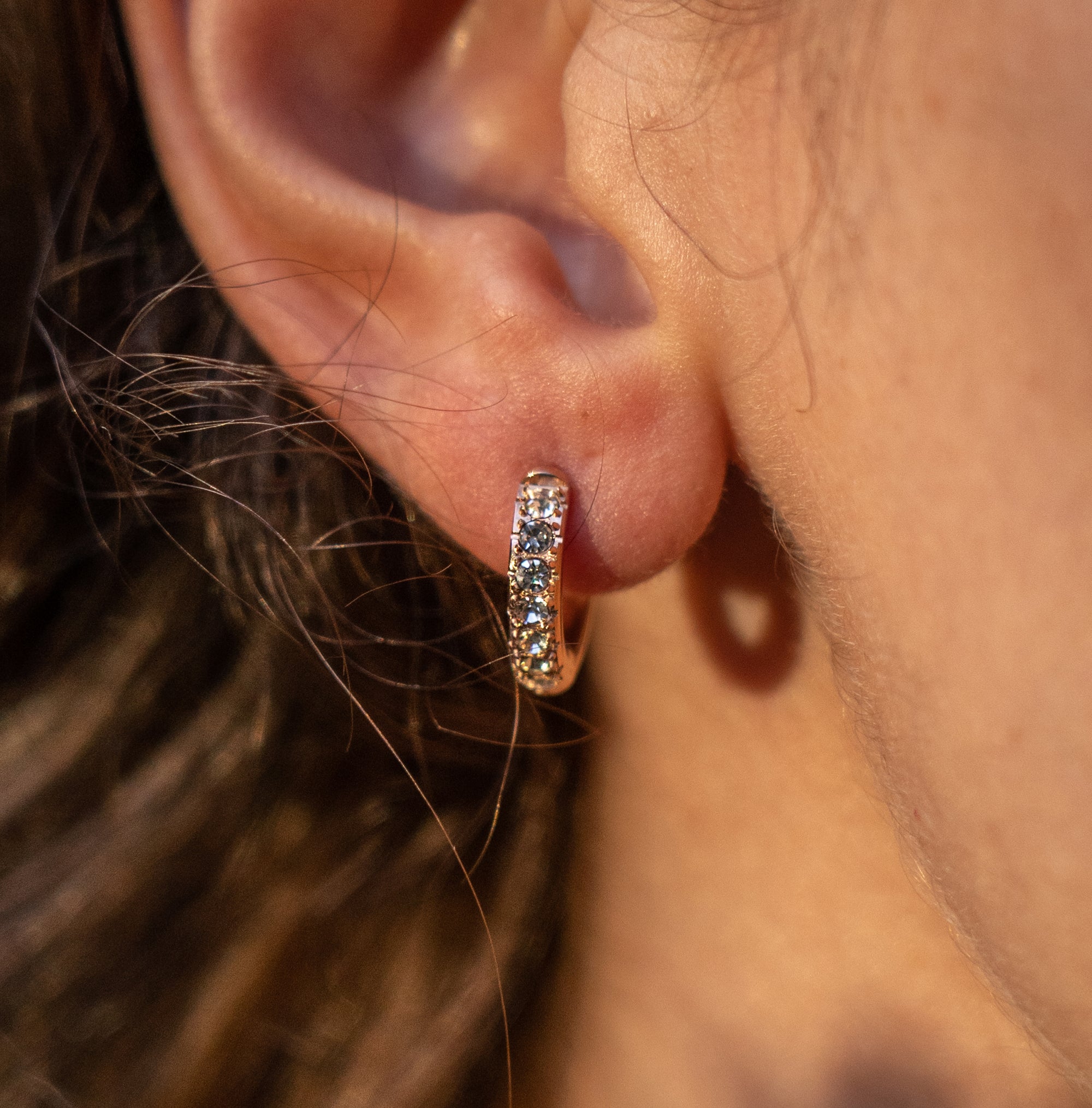 A model wearing a rose gold hoop earring with little crystals.