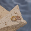 A pair of hoop earrings that are gold and rose gold with little crystals.