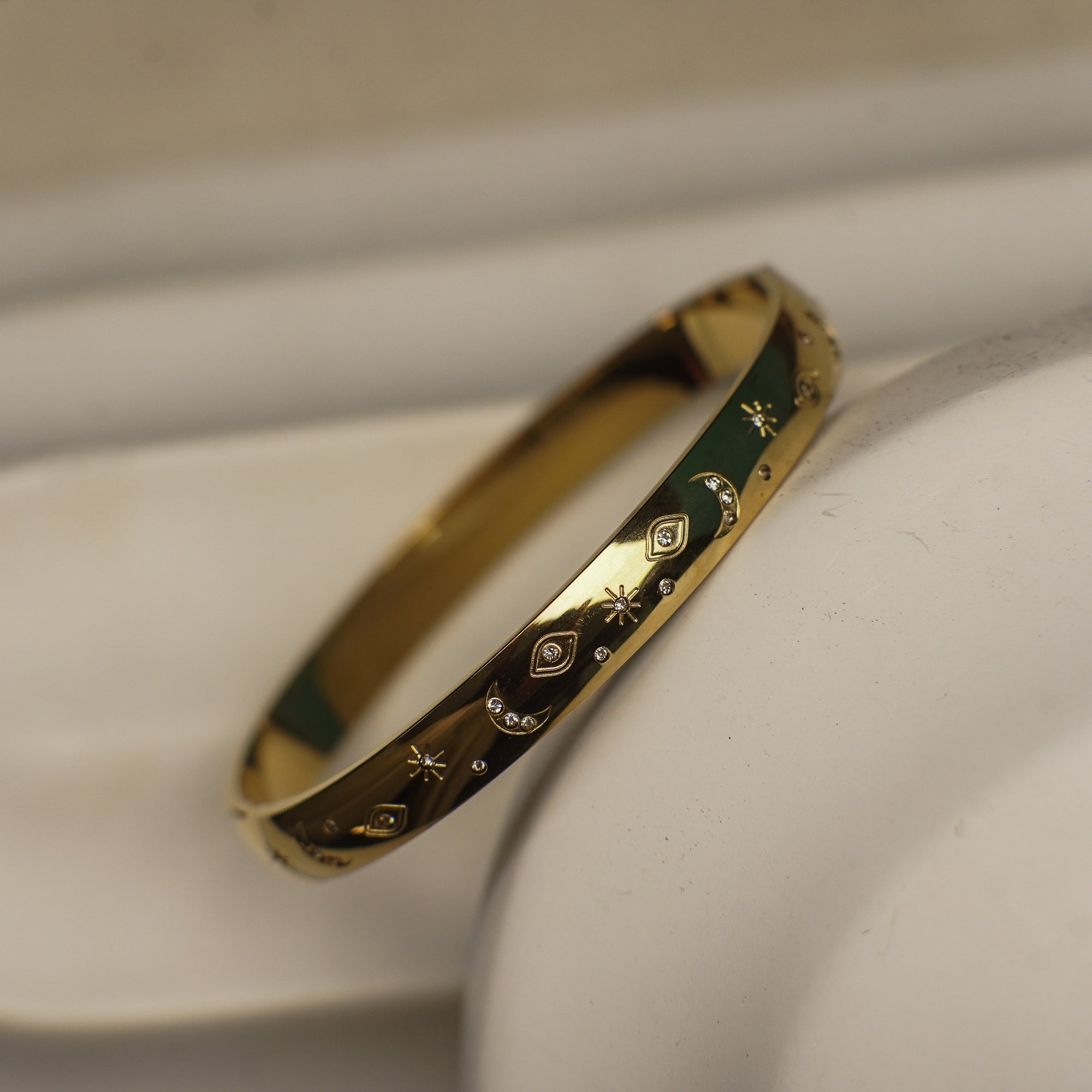 Gold bracelet with intricate designs on a white surface