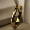 Gold bracelet with intricate designs on a neutral background