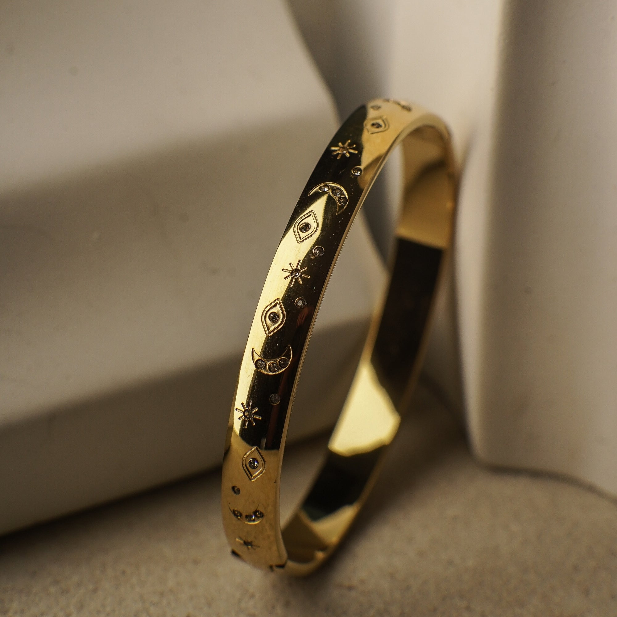 Gold bracelet with intricate designs on a neutral background