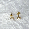 Gold earrings with pearl-like stones on a textured white background