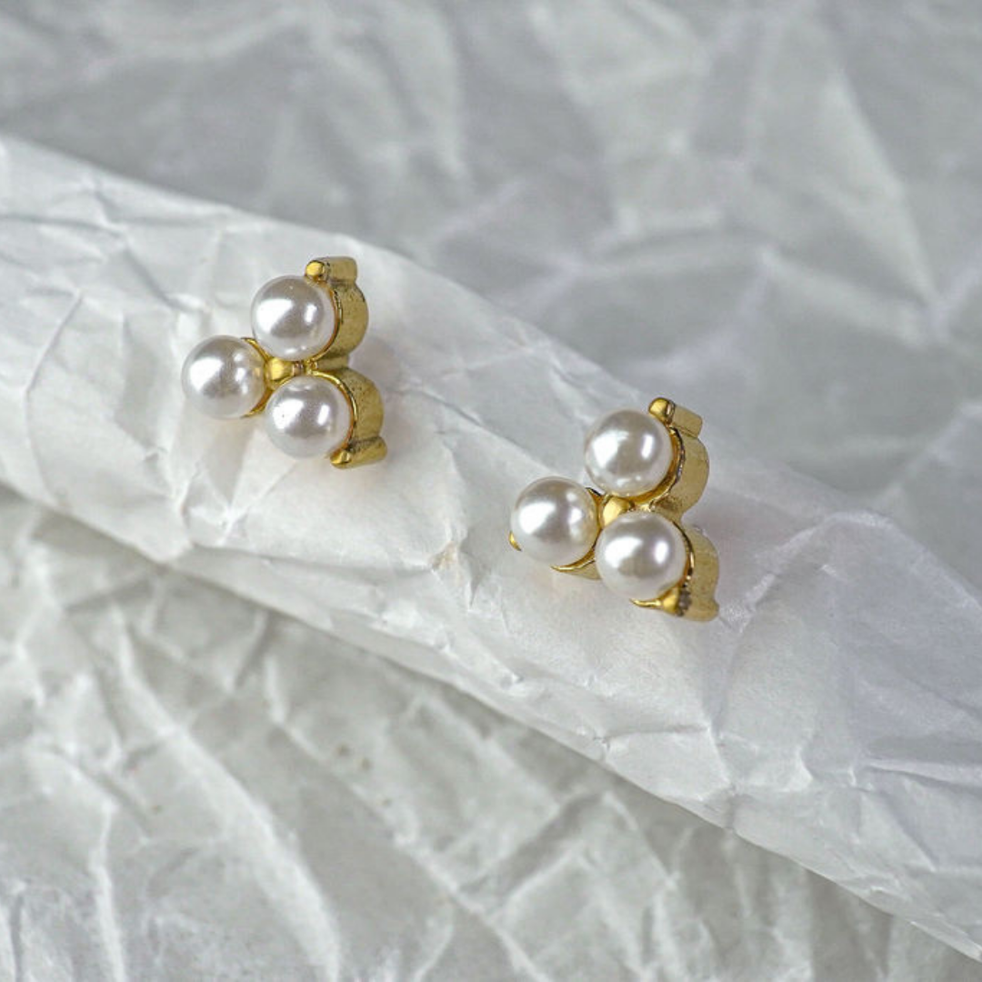 Pair of pearl earrings with gold accents on a white fabric background