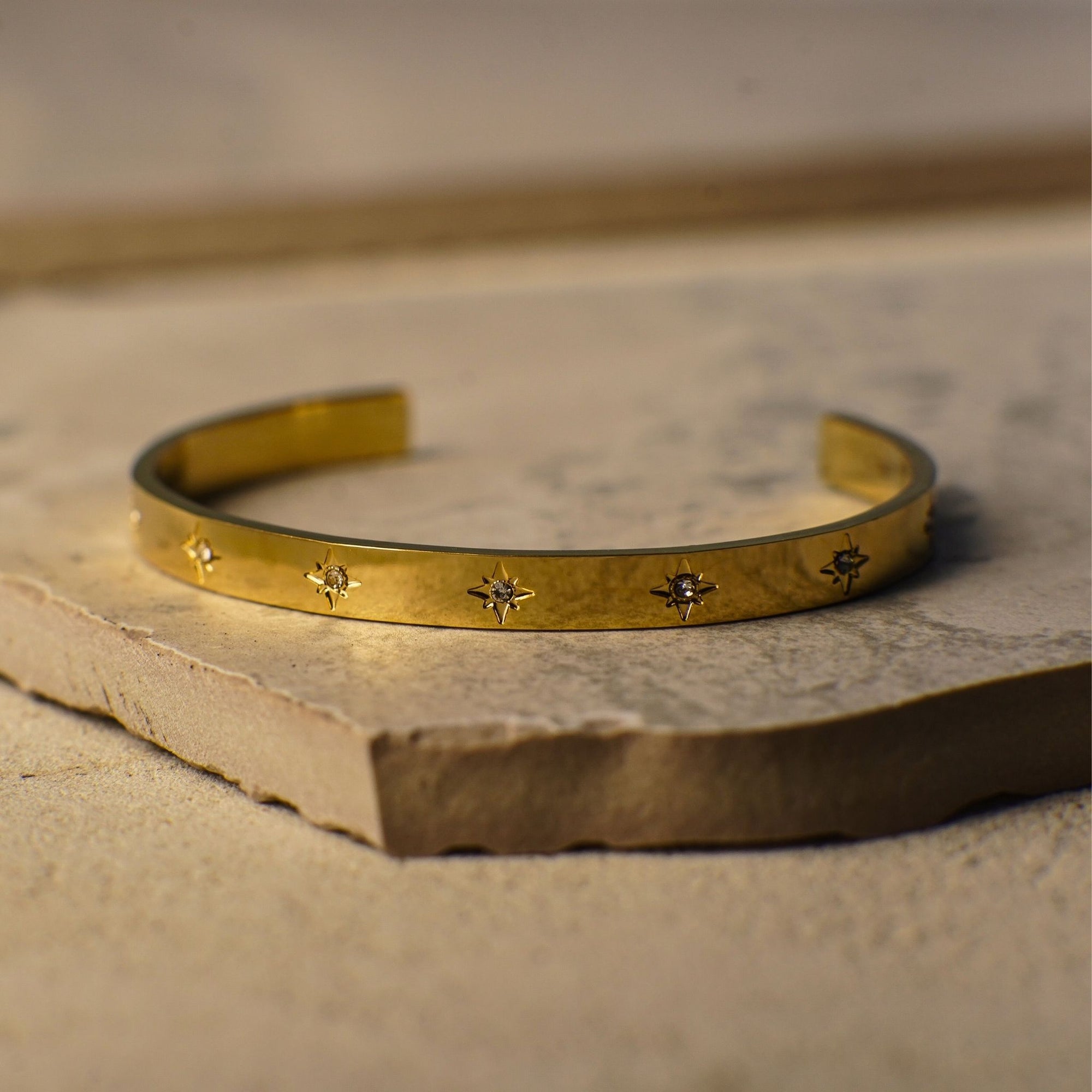 Gold bracelet with star designs on a stone surface