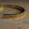 Gold bracelet with star-shaped embellishments on a textured surface