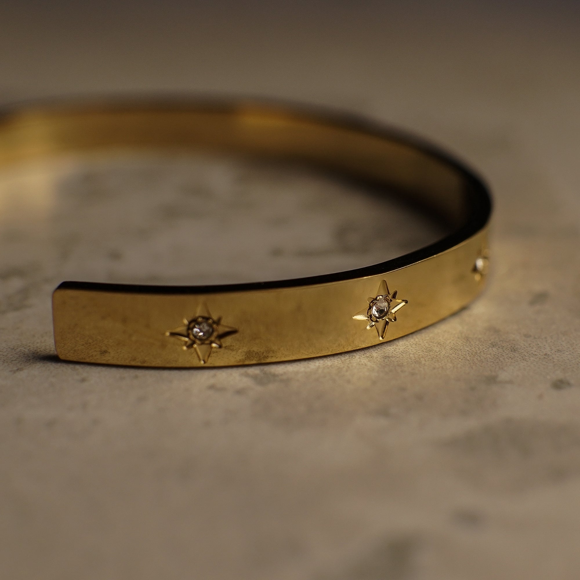 Gold bracelet with star-shaped embellishments on a textured surface