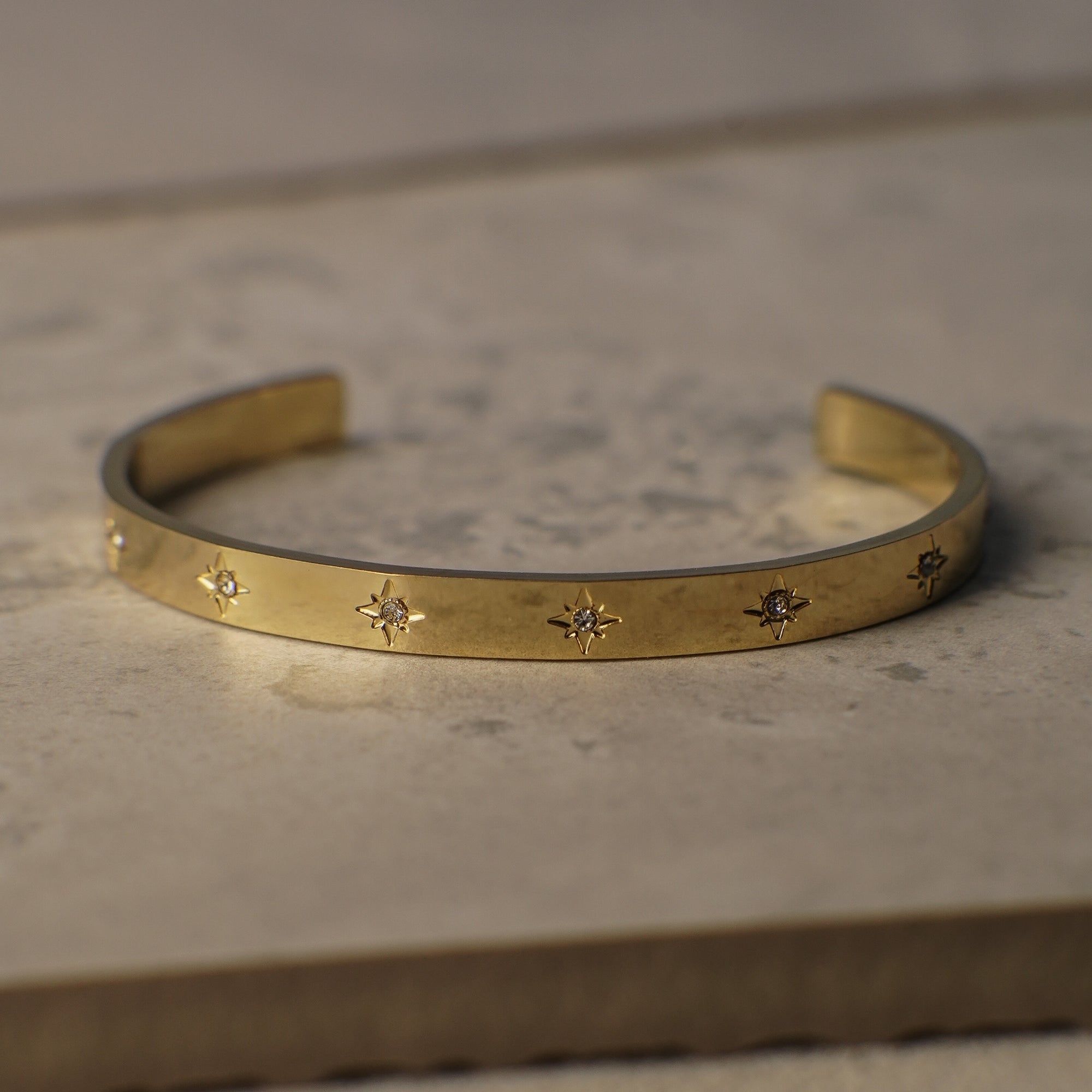 Gold bracelet with star designs on a stone surface