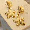 Gold starfish earrings on a beige background